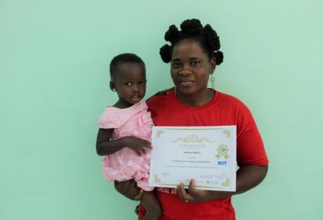 Susana Amble, shows off her ICT certificate while holding her youngest child, 3-year-old Precious Aidoo